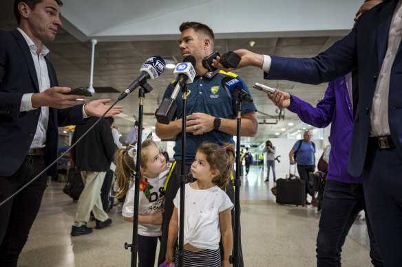 David Warner gets some help from his daughters as he speaks to the press at Melbourne Airport.