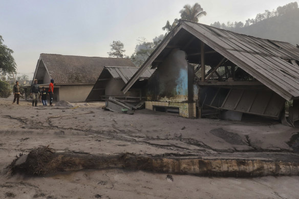 Villagers inspect the damage as houses are seen buried in volcanic ash from the eruption of Mount Semeru in Kajar Kuning village in Lumajang, East Java, Indonesia, on Monday.