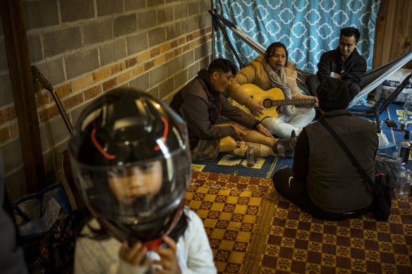 Eh Klu Ba Shwe (back left) enjoys a song and a beer with friends at his temporary share home in Ararat.