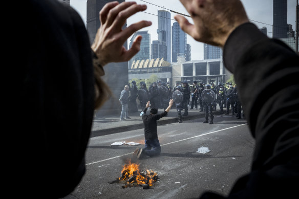 A protester is seen raising hands in front of police.