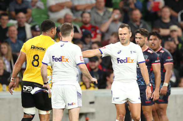 Referees speak with Ardie Savea, of the Hurricanes, during the match against the Rebels.