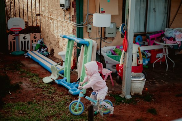 Nova Pearce plays in her front yard in south Broken Hill. Her family moved to temporary accommodation this year while taxpayer-funded remediation works were completed to remove lead from the home and yard. 