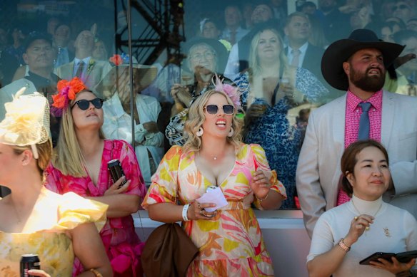 The crowd cheers on the field as they pass the finish line.
