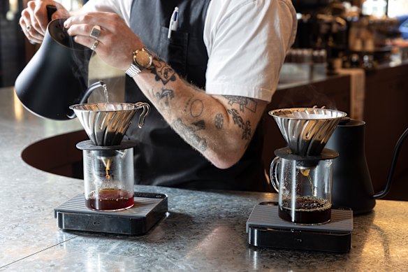 The barista pours 91C hot water over the coffee grounds, and the coffee then drips down through the filter into the glass beaker. 