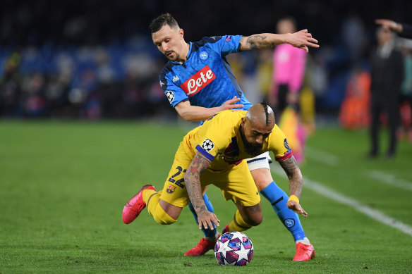 Mario Rui of Napoli (in blue) vies with Barcelona's Arturo Vidal.