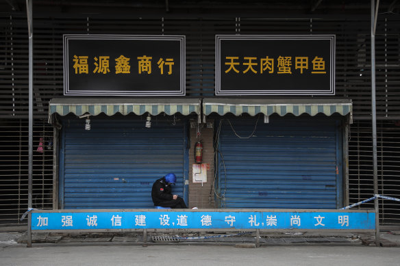 A security guard sits outside the Huanan Seafood Wholesale Market in Wuhan, which was closed on New Year’s Day for cleaning.