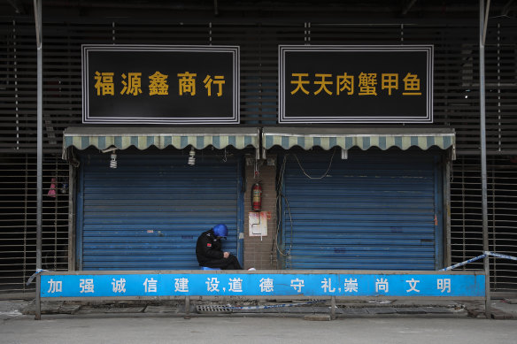 A security guard sits outside the closed Huanan Seafood Wholesale Market, 