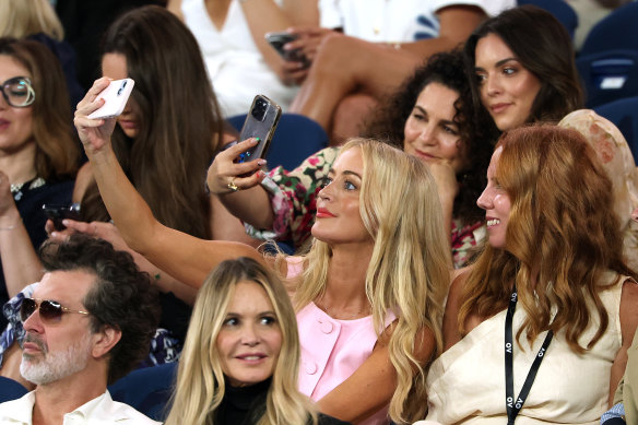 Jackie O takes a selfie as she sits behind Doyle Bramhall and Elle Macpherson at Rod Laver Arena.