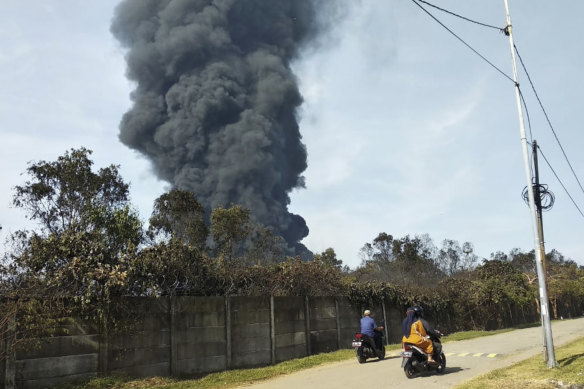 Motorists ride past as thick smoke billows from a fire that razes through Pertamina Balongan Refinery in Indramayu, West Java, Indonesia, on Monday, March 29, 2021. 