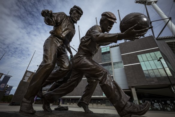 The statue outside the MCG of Wills  (left) umpiring the 1858 game between Melbourne Grammar and Scotch College.