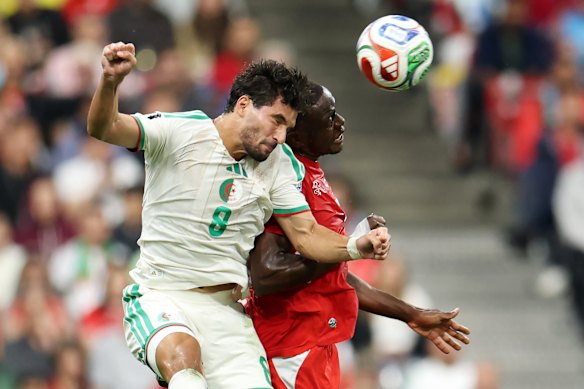 Houssem Aouar (8) of Algeria competes for a header against Denis Zakaria (6) of Switzerland.