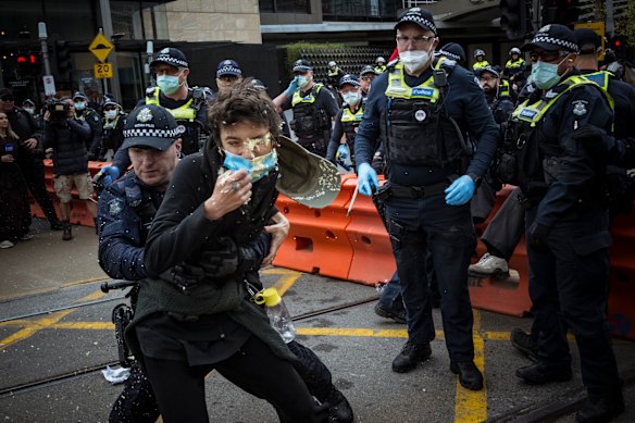 Police tackle a protester who has been hit with capsicum spray.