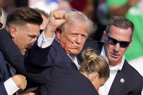 Donald Trump is helped by Secret Service agents after the shooting.