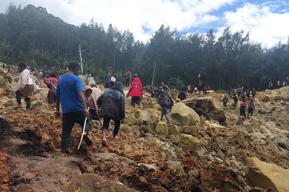 People cross over the landslide area to get to the other side in Yambali village, Papua New Guinea, on Friday.