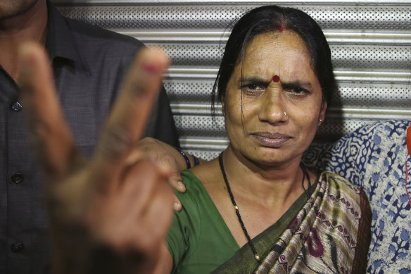 Asha Devi, mother of the victim of the fatal 2012 gang rape on a moving bus, displays a victory sign after the rapists of her daughter were hanged, in Delhi.