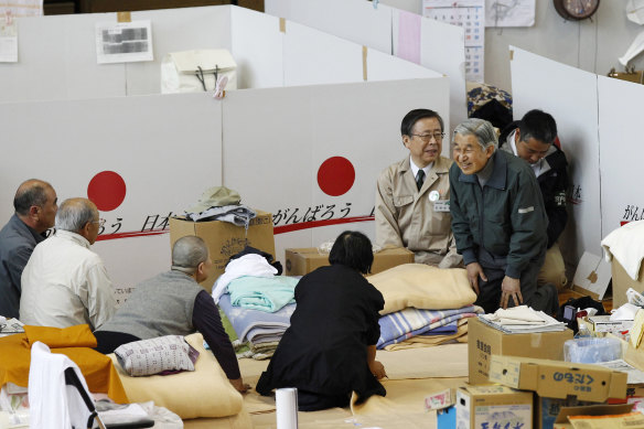 Akihito, in green, talks to evacuees after Fukushima in 2011.
