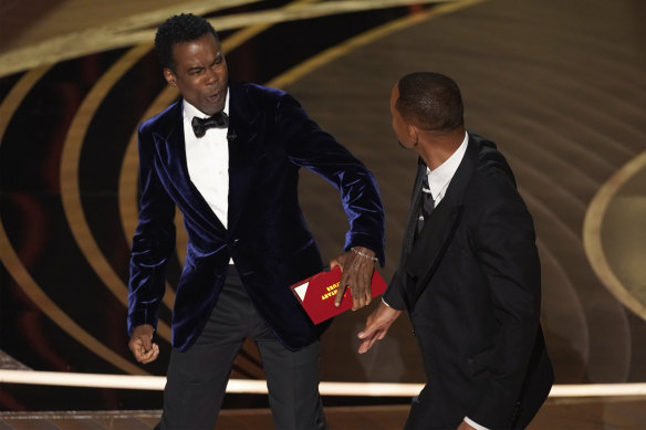 Chris Rock, left, reacts after being hit on stage by Will Smith while presenting the award for best documentary feature at the Oscars.