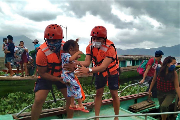 Members of the Philippine Coast Guard carry a child as they are evacuated to safer ground in Camarines Sur province, eastern Philippines as they prepare for Typhoon Goni. 