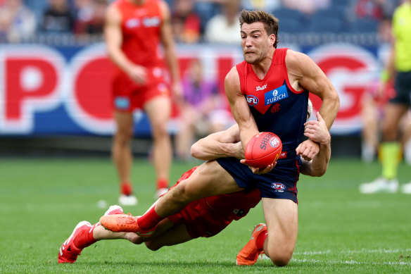 Jack Viney handballs under huge pressure from Sun Sam Flanders.