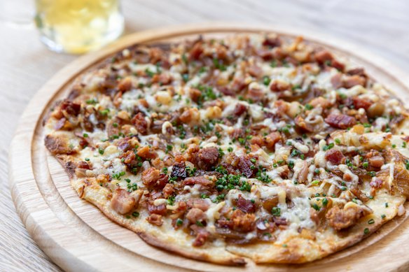 Flammkuchen (Alsatian flatbread) scattered with bacon, chives and creme fraiche.