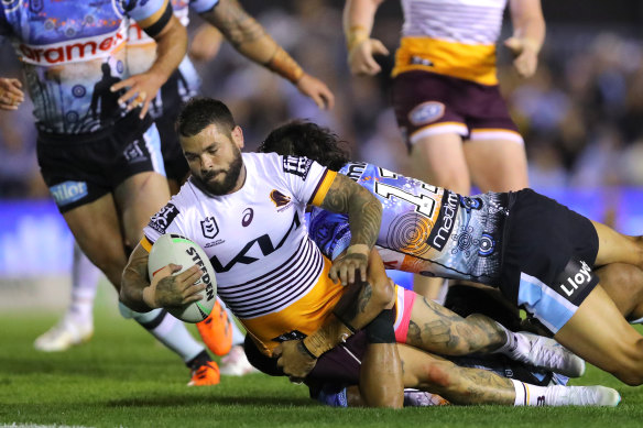 Broncos captain Adam Reynolds is grounded by Sharks defenders.