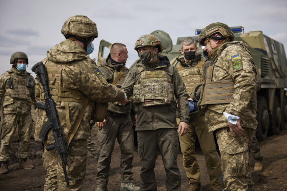 Ukrainian President Volodymyr Zelenskiy shakes hands with a soldier as he visits the war-hit Donbas region, eastern Ukraine, Thursday, April 8, 2021. 