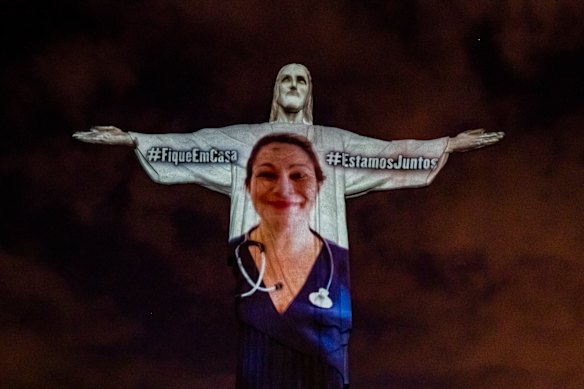 A medical worker is projected onto the illuminated statue of Christ the Redeemer as Archbishop of the city of Rio de Janeiro Dom Orani Tempesta performs a mass on Easter Sunday.