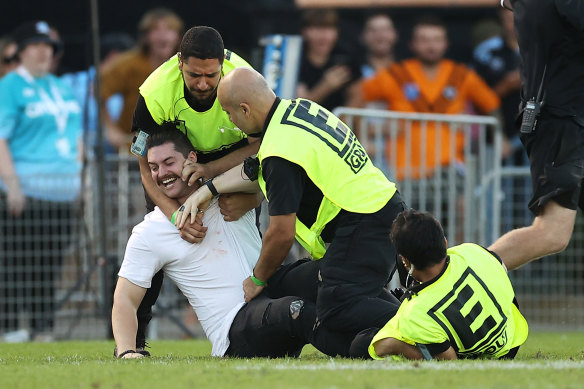 Held: A pitch invader is wrestled to the ground by security.
