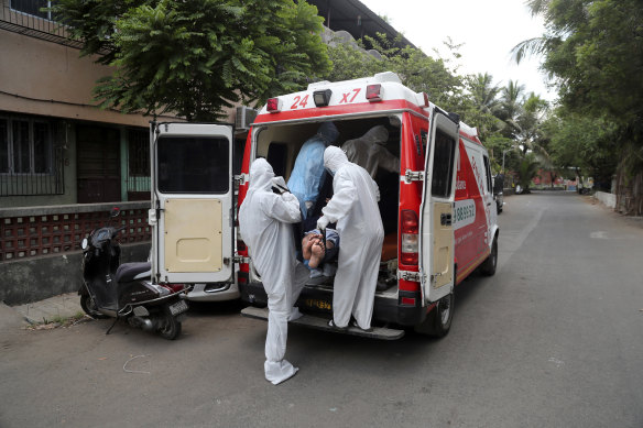 Izhaar Hussain Shaikh, left, picks up a COVID-19 patient from his home in Mumbai, India.