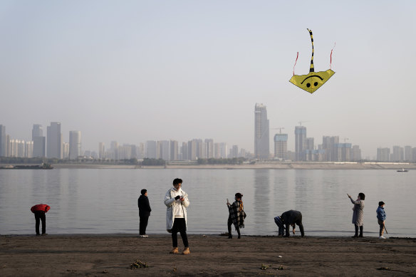 A man flies a kite as people walk along the coast of the Yangtze River at Jiangtan park in Wuhan.