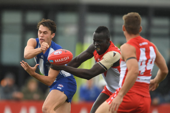 North Melbourne's Curtis Taylor gets a hand pass away despite the attention of Sydney's Aliir Aliir in Hobart on Monday.