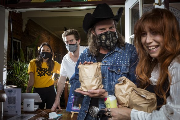 Chewy Tjoe and Will Ewing (rear) give free meals to musicians Ben Mastwyk and Ruby Jones at  Brunswick Ballroom.