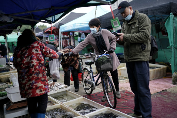 Vendors selling fish in an open market in Wuhan, China, a year after the start of the pandemic.