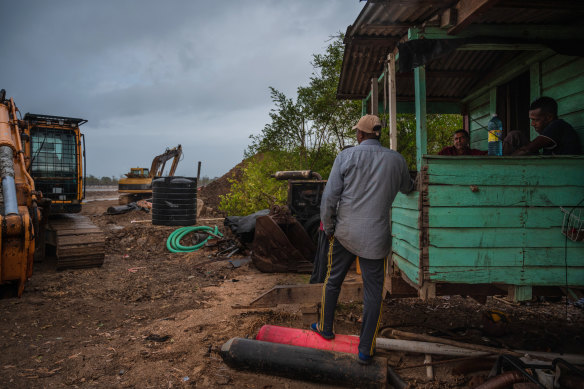 Workers wait for a storm to pass before continuing to repair a breached sea wall in Mahaicony, Guyana.