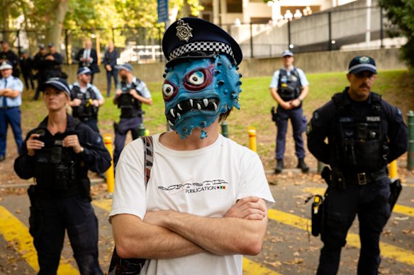 A protester mocks police officers as protesters gather around the Surry Hills Police Station.