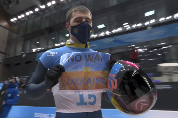 Vladyslav Heraskevych holds his “No War in Ukraine” sign after finishing a run at the men’s skeleton competition at the 2022 Winter Olympics. 