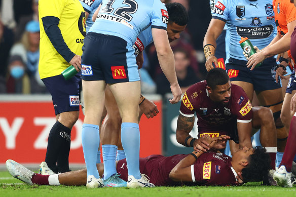 Queensland’s Selwyn Cobbo of the Maroons is attended to by Dane Gagai of the Maroons early in game three.