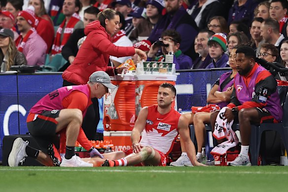 Tom Papley of the Swans is treated by medical staff.