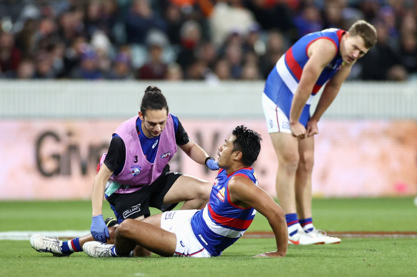 Lin Jong is assisted after injurying his hamstring.