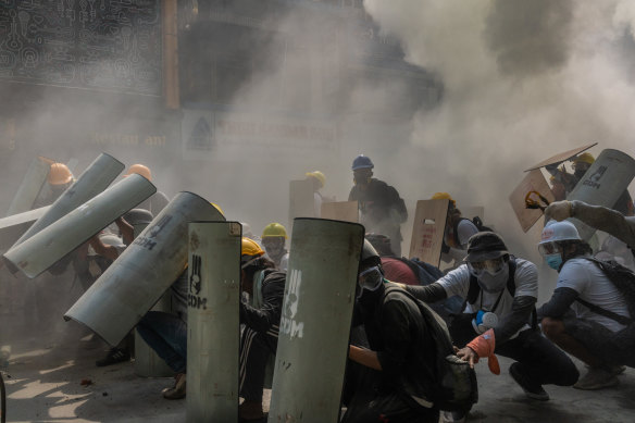 Protesters defend themselves with makeshift shields during clashes with riot police in Yangon in February. Hundreds of people have been killed by the military junta since the February 1 coup.