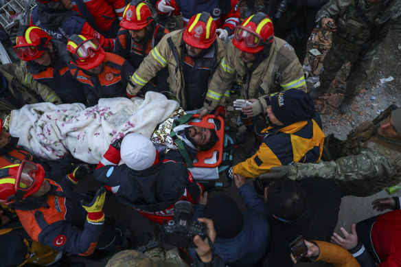 Turkish rescue workers carry Ergin Guzeloglan, 36, to an ambulance after he was pulled out from a collapsed building five days after the quake. 