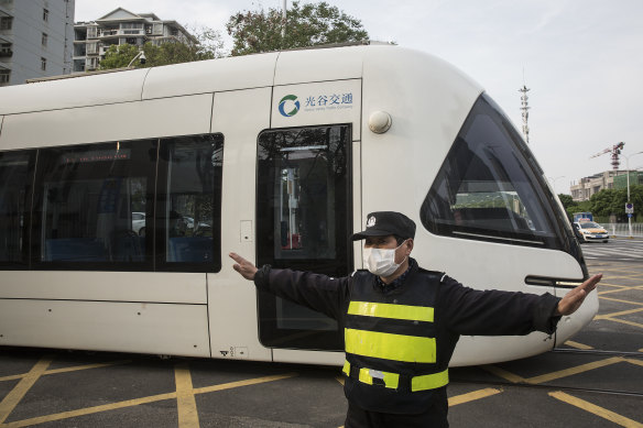 A security officer protects a tram as operations resume on two lines in Wuhan, China, on Wednesday.