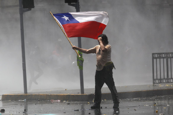 A demonstrator holds a Chilean flag.