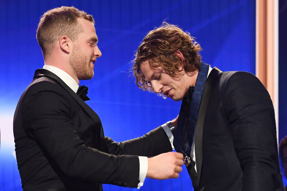 Tom Mitchell presents Nat Fyfe with the 2019 Brownlow Medal.