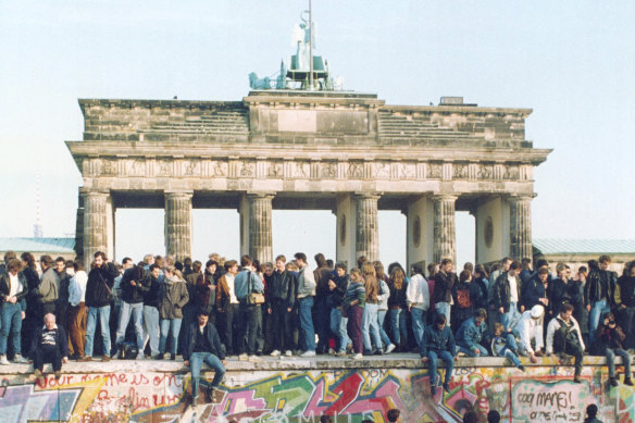 Germans from East and West stand on the Berlin Wall in front of the Brandenburg Gate in the momentous month of November 1989.