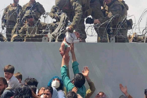 A baby is lifted across a wall at Kabul Airport in Afghanistan by US soldiers. 