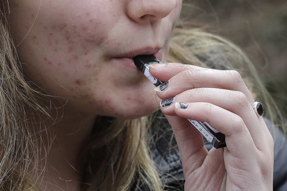 A high school student uses a vaping device near a school campus in the US.