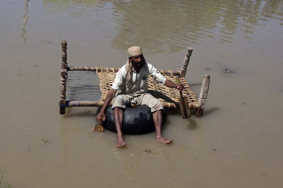 A displaced man carries belongings he salvaged from his flood-hit home as he paddles through a flooded area, on the outskirts of Peshawar, Pakistan, on Sunday.
