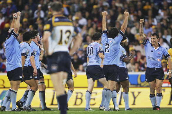 Brumbies captain Stirling Mortlock stands dejected as Waratahs players celebrate victory at Canberra Stadium in 2005.