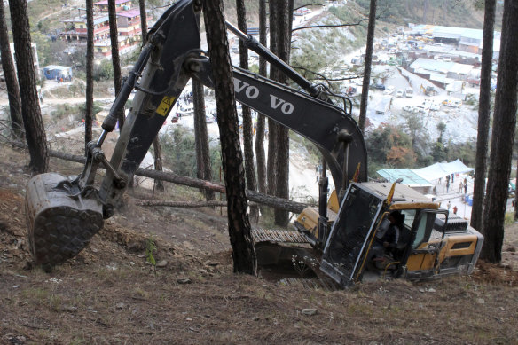 An earth-mover makes a vertical drill on the top of a mountain where a tunnel that collapsed in Uttarakhand state.